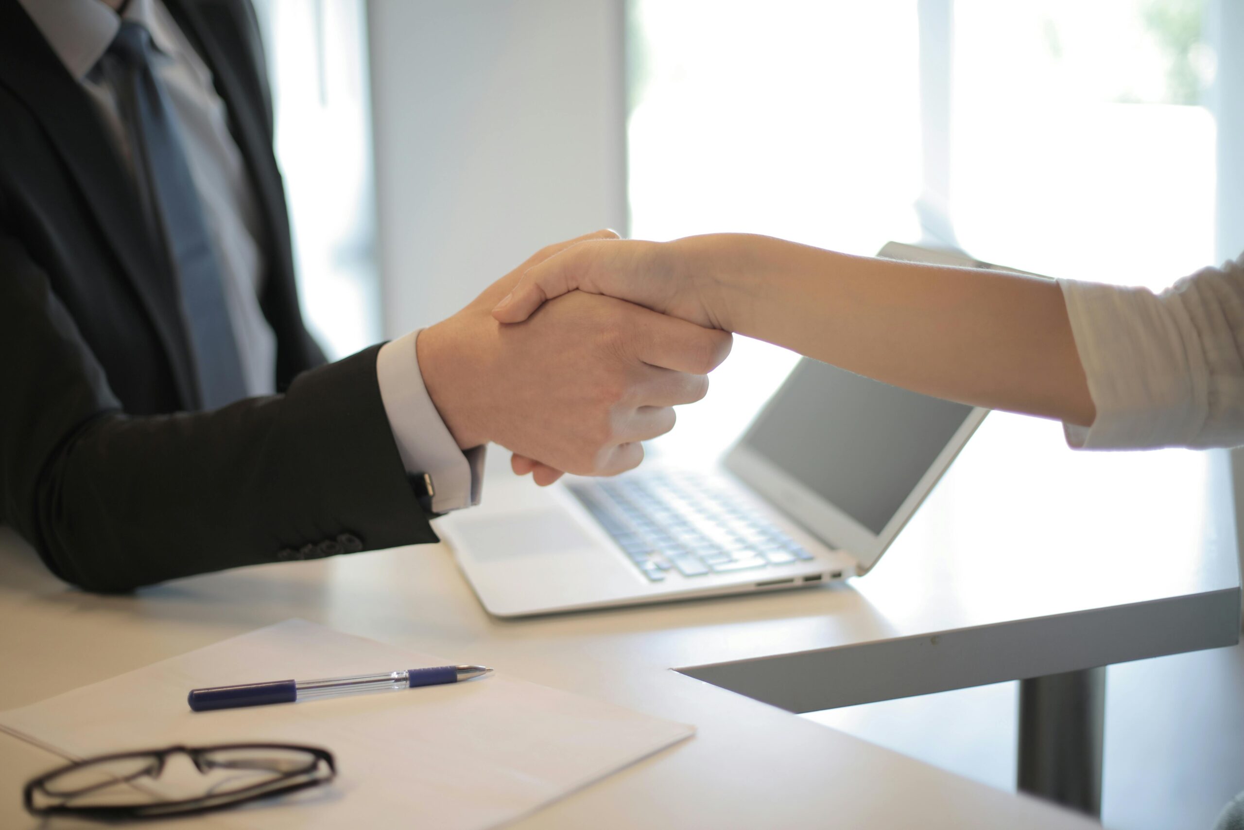 two people shaking hands over a desk